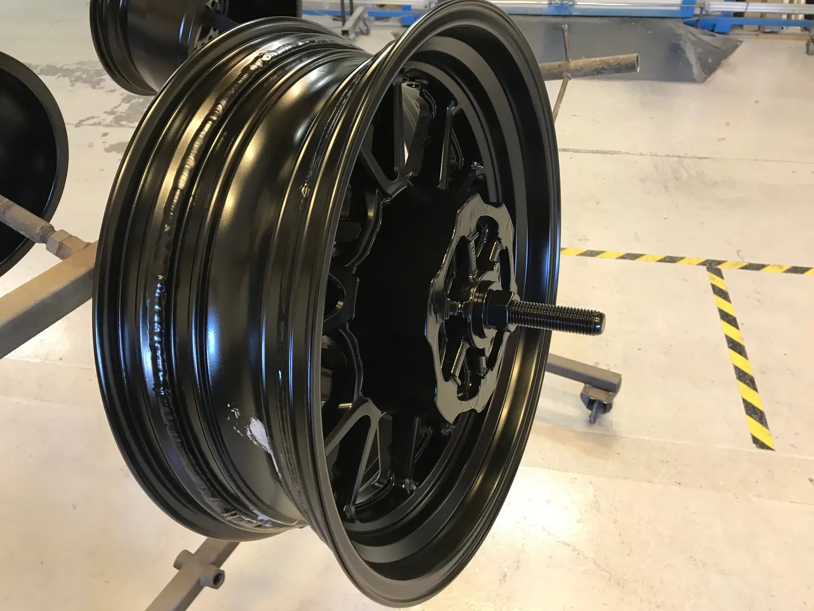 Breddad och svartlackerad MC-fälg uppspänd i maskin efter modifiering hos Fälgfixarna