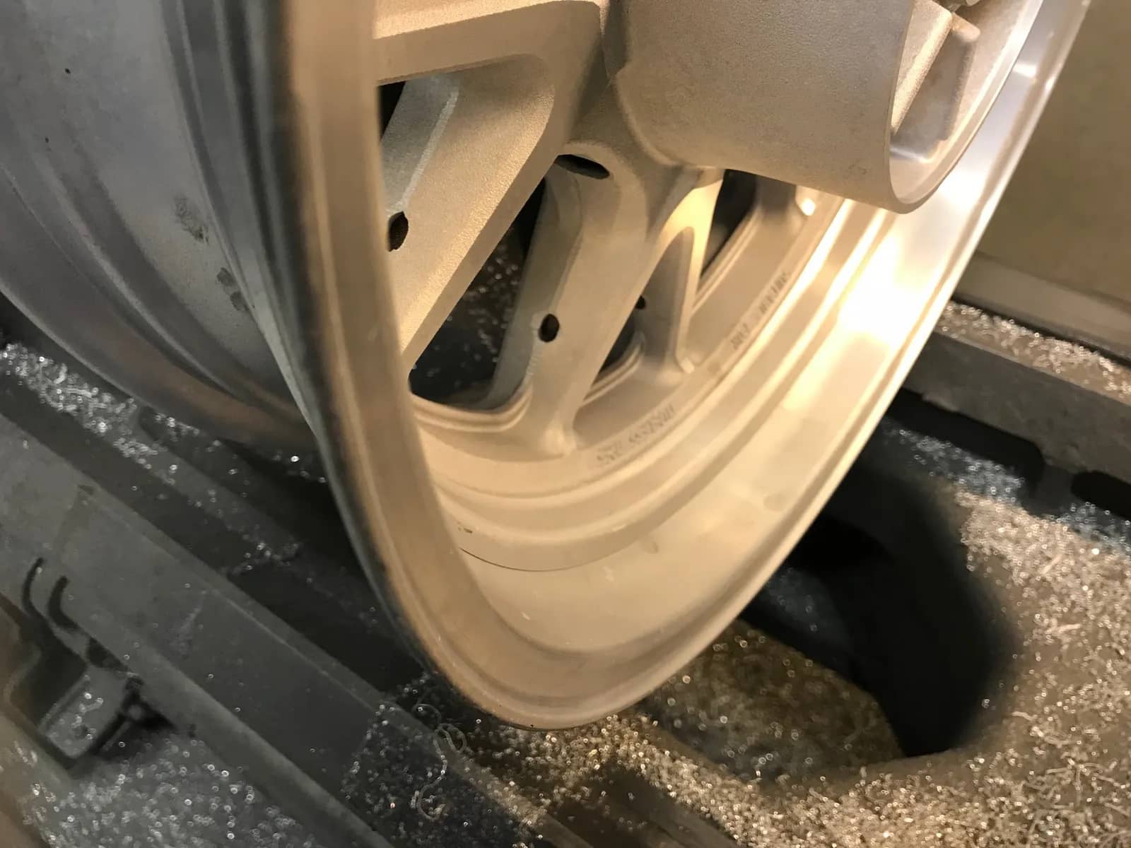 Avlackerad MC-fälg i rent aluminium uppspänd i maskin, redo för vidare bearbetning